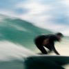 Surfeur glissant à pleine vitesse sur une vague verte.