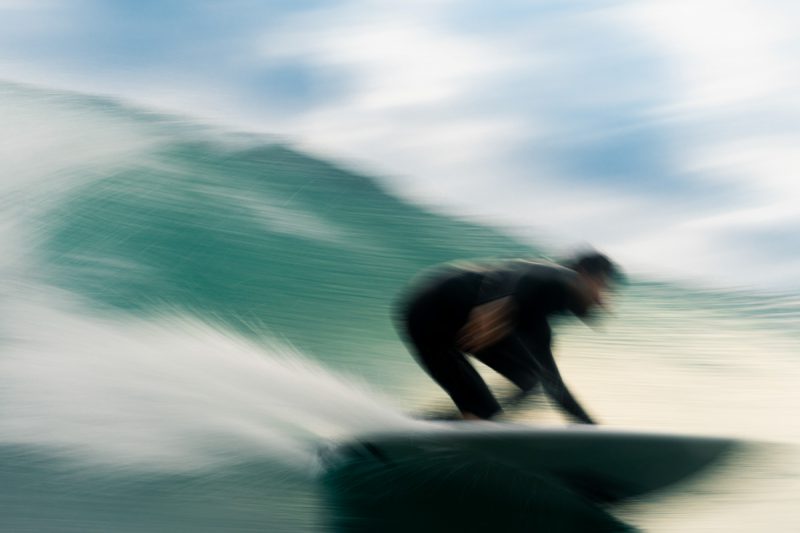 Surfeur glissant à pleine vitesse sur une vague verte.