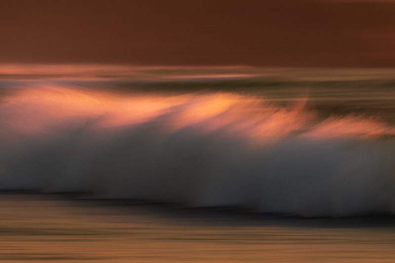 La mousse d'une vague coloré par la couleur rose d'un coucher de soleil.